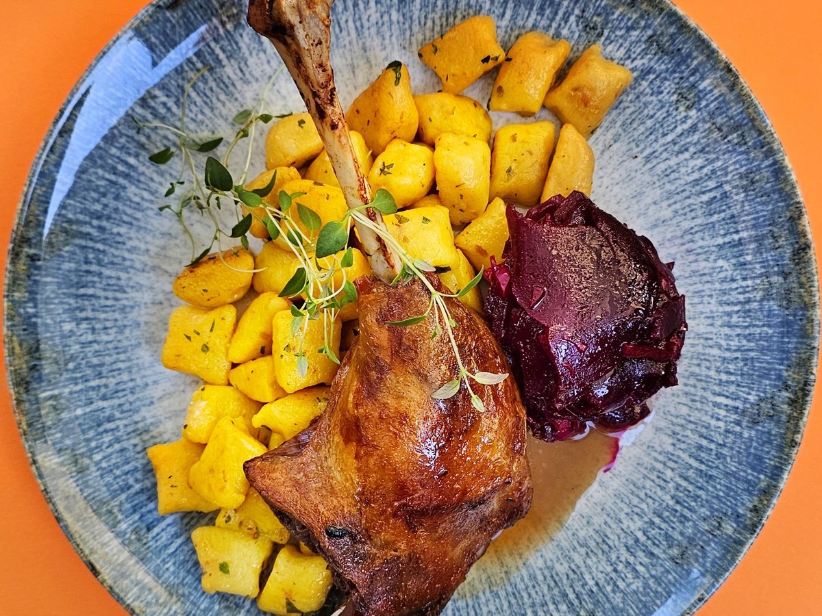 Duck leg with dumplings and red cabbage on a blue plate
