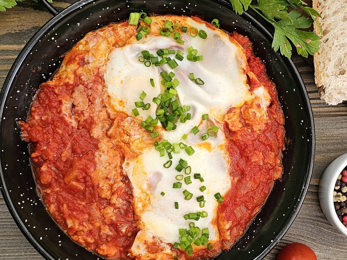 Shakshuka in a cast-iron skillet with two eggs and chives